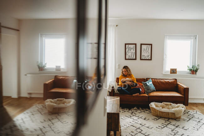 Sala de estar vista de mãe branca amamentando bebê recém-nascido no sofá — Fotografia de Stock