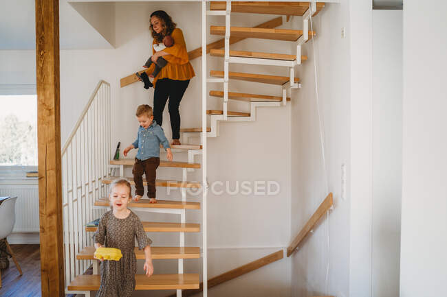 Mutter und Kinder gehen während der Quarantäne zu Hause die Treppe hinunter — Stockfoto
