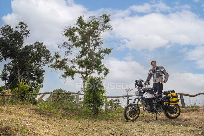 Молодой человек рядом с мотоциклом на дороге — стоковое фото