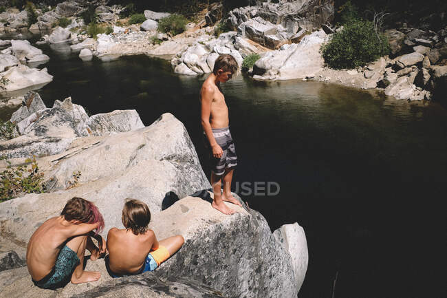 Мальчики осматривают скалу над рекой — стоковое фото