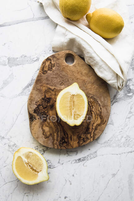 Лимонні скибочки на білій тарілці на дерев'яному фоні. вид зверху . — стокове фото