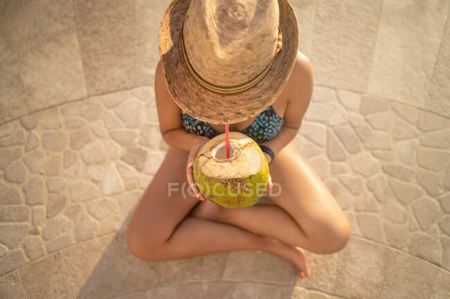 Donna felice rilassarsi in piscina e bere acqua di cocco. — Foto stock