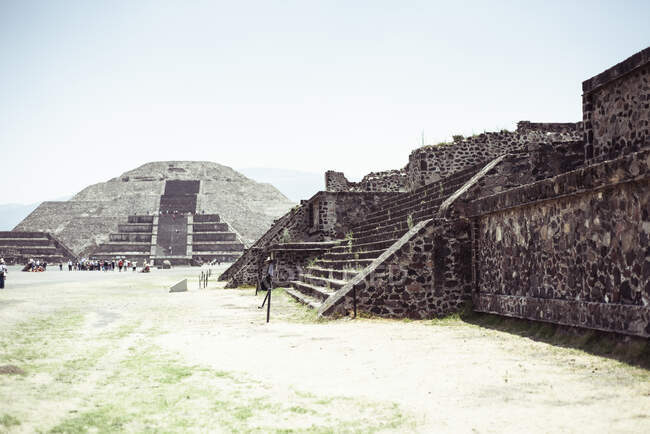 Antiguas ruinas piramidales mayas con grupo de turistas a distancia - foto de stock