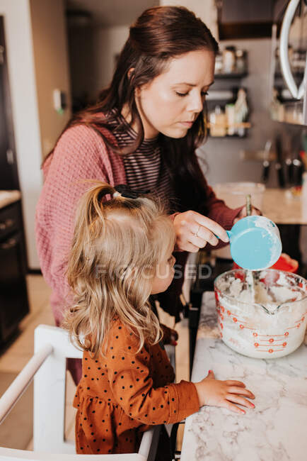 Beautiful young mother and her daughter cooking — Stock Photo