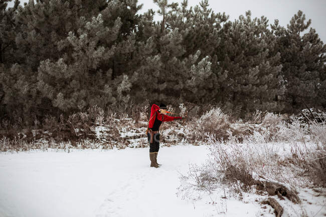 Teen boy shooting bow and arrow in wintery Wisconsin field — Stock Photo