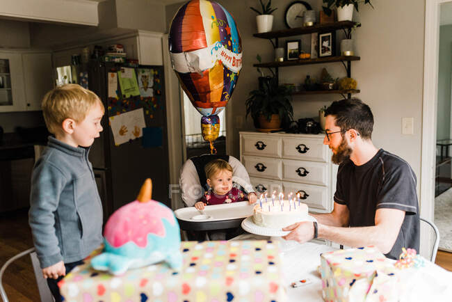 Um ano de idade comemorando aniversário com a família à mesa com bolo — Fotografia de Stock
