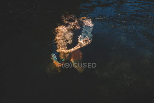 Niño lleva una piedra sumergida bajo agua arrugada - foto de stock