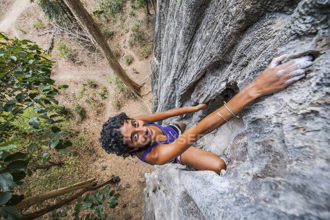 Высокий угол обзора женщины, поднимающейся по крутой известняковой скале в Лаосе — стоковое фото