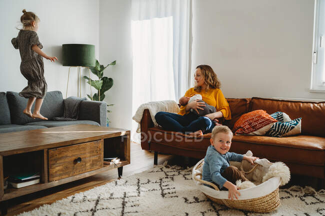 Life with a new baby, mother breastfeeding and older kids going wild — Stock Photo