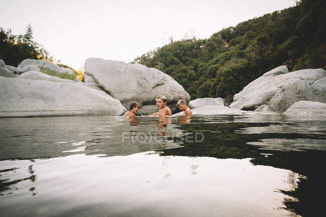 Trois amis reposent dans une piscine d'eau au crépuscule — Photo de stock