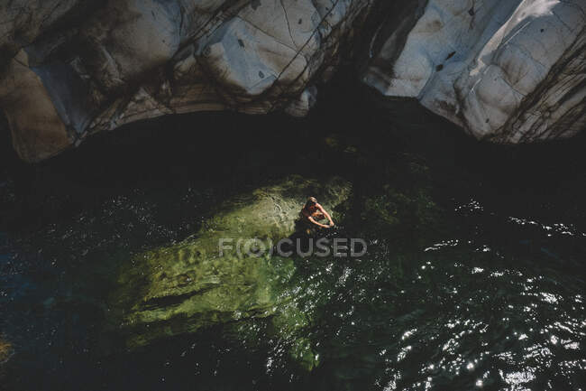 Weitwinkelblick einer Frau, die auf einem Felsen in einem grünen Wasserbecken sitzt — Stockfoto