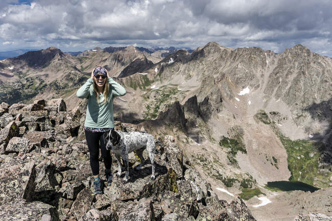 Felice escursionista femminile escursioni con cane in montagna contro cielo nuvoloso — Foto stock