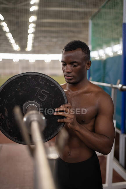 African American athlete putting heavy weight on bar during workout in stadium — Foto stock