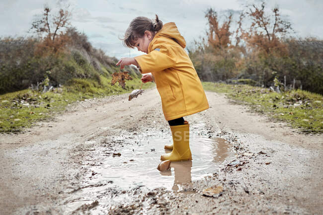 Ein 2-jähriges Mädchen spielt mit einer Schlammpfütze — Stockfoto