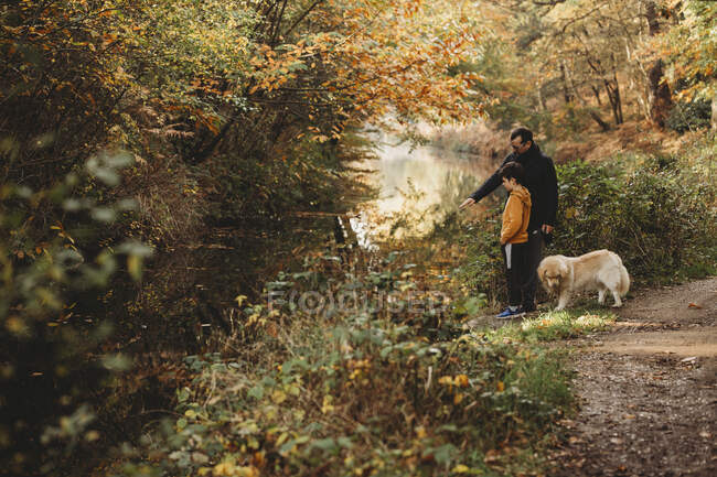 Father pointing at canal with son and dog in fall — Stock Photo