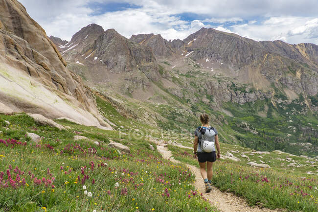 Vista trasera de la mujer senderismo en la montaña durante las vacaciones - foto de stock