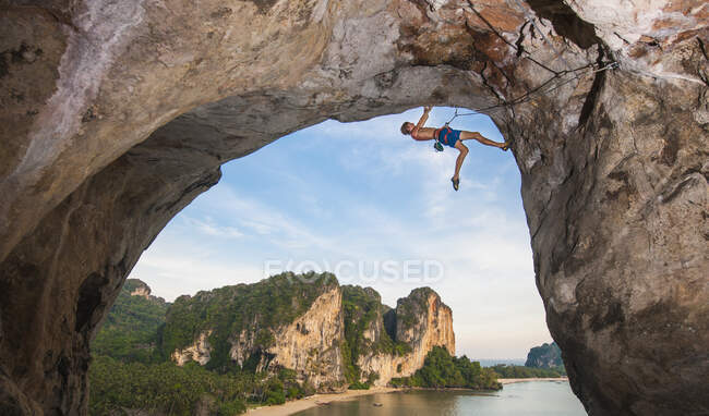 Молодий чоловік, що вилазить на скелю на пляжі Тонсай. — стокове фото