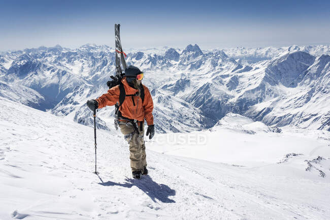 Mann mit Skistock trägt Splitboard beim Klettern auf schneebedeckten Berg im Urlaub — Stockfoto
