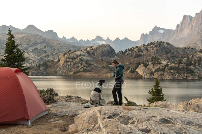 Side view of woman camping with dog by during vacation — Stock Photo