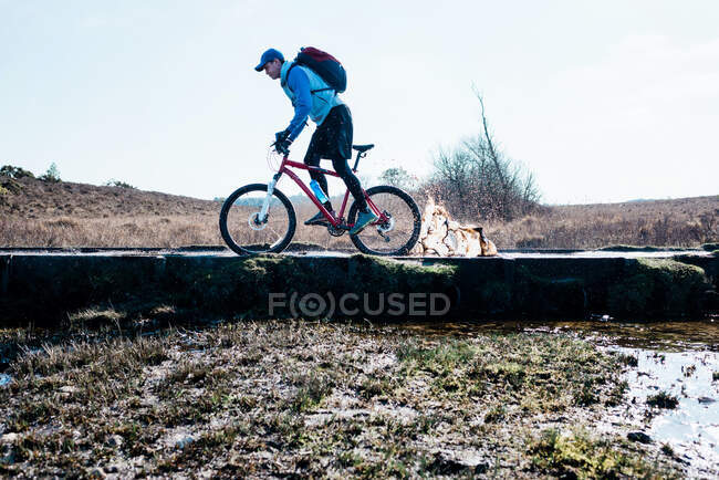 Man cycling through a muddy puddle whilst mountain biking in England — Stock Photo