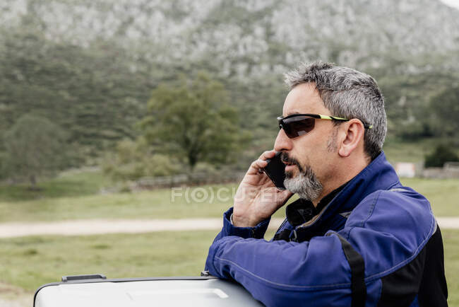 Man in sunglasses and a jacket on the phone — Stock Photo