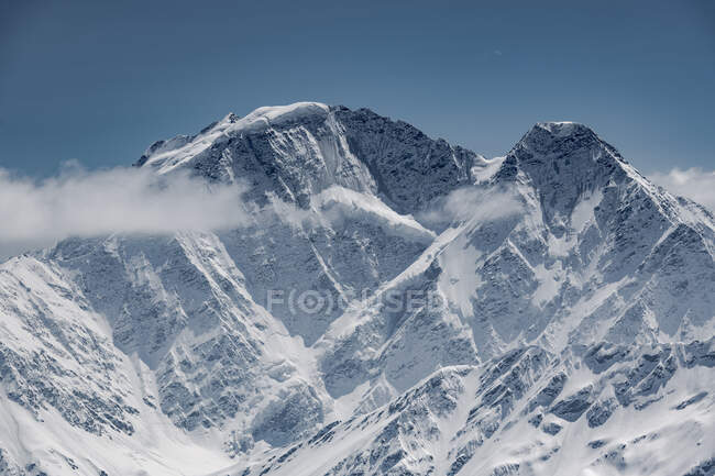 Foto idílica de montañas cubiertas de nieve contra el cielo azul - foto de stock