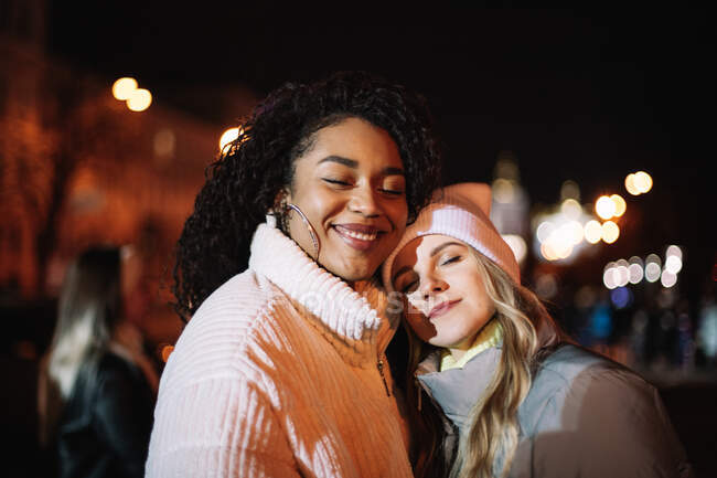 Portrait of happy girlfriends standing in city at night — Stock Photo