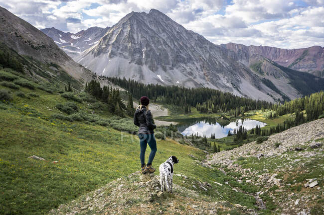 Жіночий пішохід з собакою дивиться на красиву гору — стокове фото