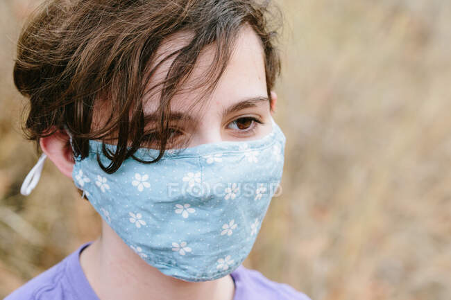 Adolescente chica con pelo corto usando una máscara facial durante la pandemia - foto de stock