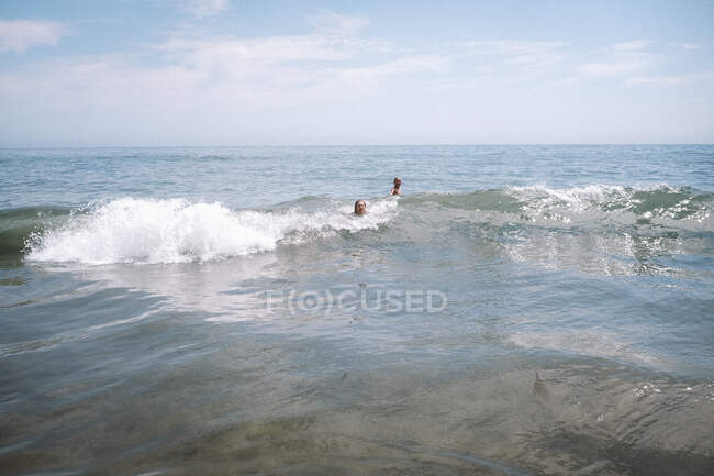 Ragazzi che giocano nelle onde al largo di una spiaggia della California — Foto stock