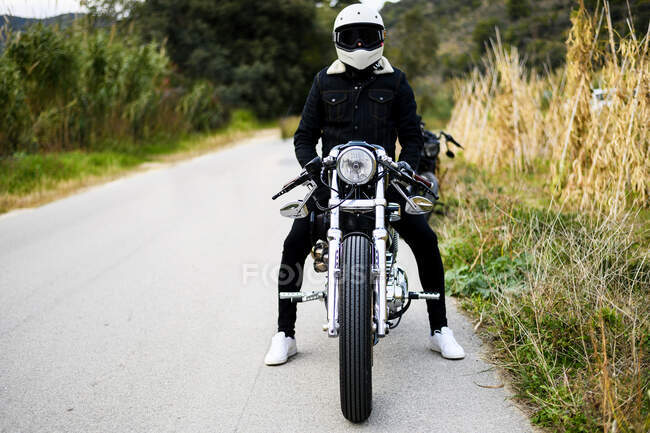 Вид спереди мотоцикла, стоящего на дороге вместе со своим владельцем — стоковое фото