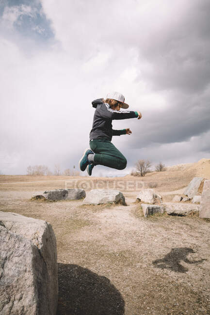 Menino pegou MidAir como ele salta de Boulder — Fotografia de Stock