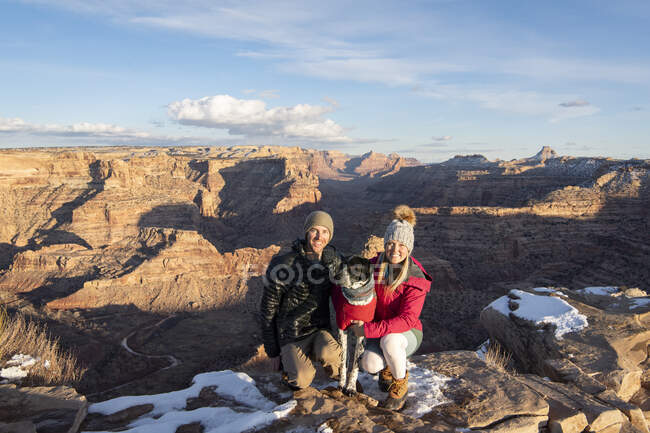 Casal feliz com cão ponteiro na montanha contra o céu durante as férias — Fotografia de Stock