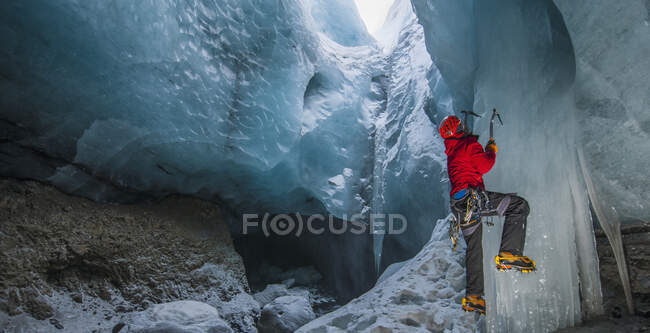 Человек карабкается на сосульку в ледниковой пещере Исландии — стоковое фото