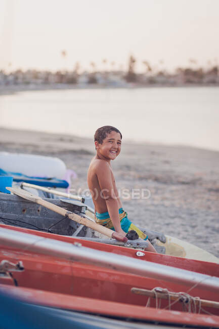 Un niño está sentado en la playa en el mar - foto de stock