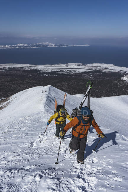 Personas con bastones de esquí escalando montañas nevadas durante las vacaciones - foto de stock