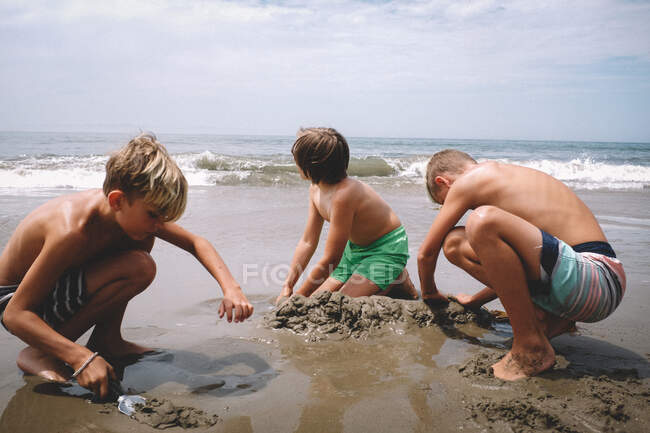 Jungen graben an einem sonnigen Sommertag im Sand — Stockfoto