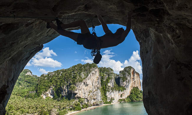 Silhouette of young man climbing overhanging rock face at Tonsai beach — Stock Photo