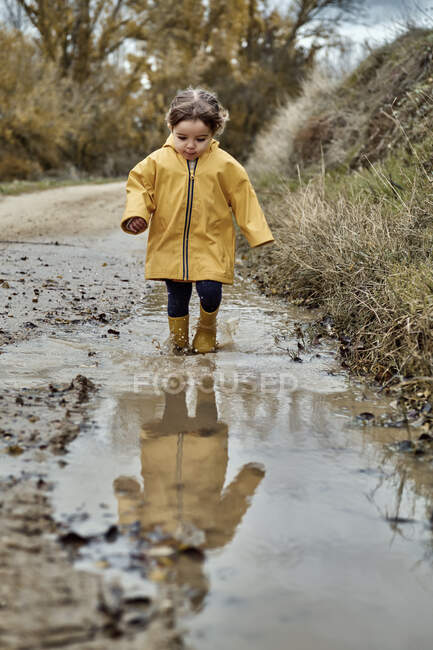 Ein 2-jähriges Mädchen spielt mit einer Schlammpfütze — Stockfoto