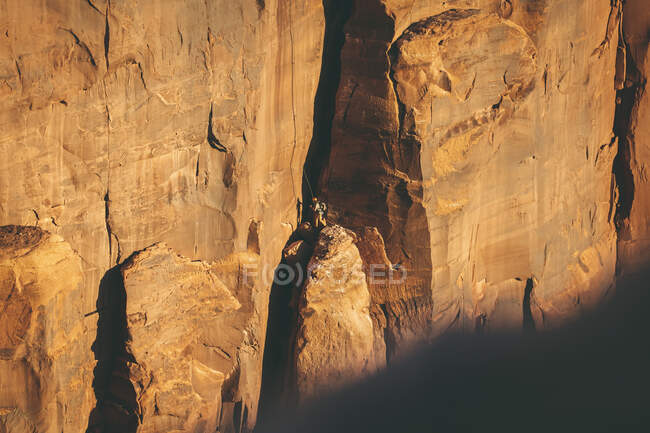 Людина піднімається на скелясту скелю в національному парку Каньйонлендс. — стокове фото
