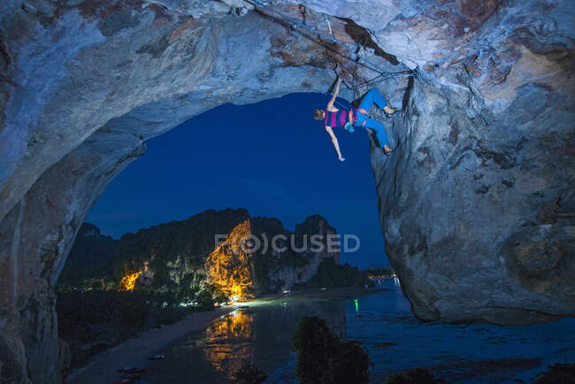 Junger Mann klettert nachts über Felswand am Tonsai-Strand — Stockfoto