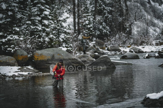 Pêche à la mouche femme debout dans la rivière pendant l'hiver — Photo de stock