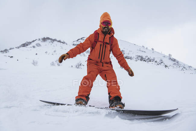 Homem sorridente snowboard na montanha nevada em férias — Fotografia de Stock