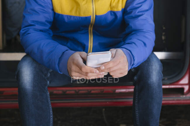 Reisender Mann benutzt Mobiltelefon während er im Wohnmobil sitzt. — Stockfoto