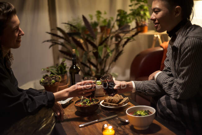 Dos mujeres en casa aplauden sobre una mesa de cena saludable sonriendo - foto de stock