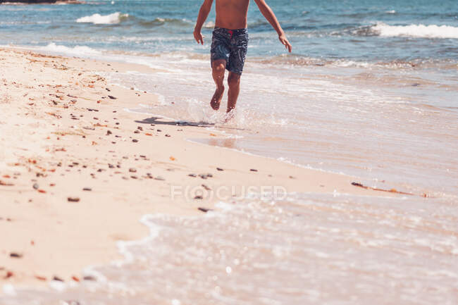Lower body - boy running on the beach. — Stock Photo