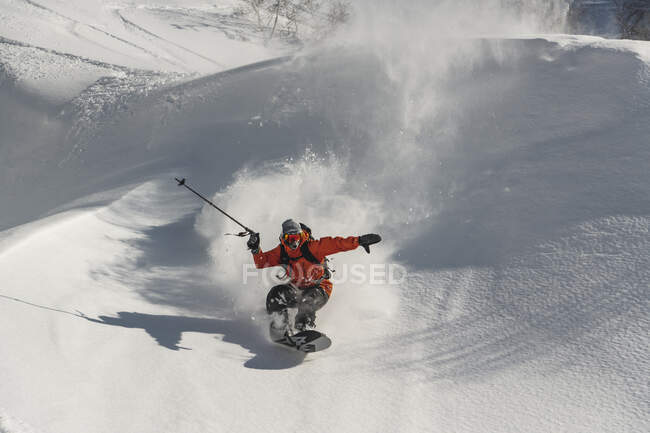 Mann in warmer Kleidung beim Snowboarden auf schneebedecktem Berg im Urlaub — Stockfoto