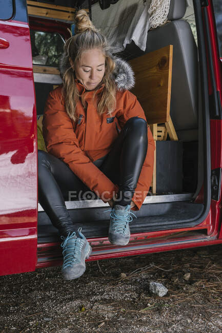 Traveler woman putting on her shoes in a camper van before going on a — Stock Photo
