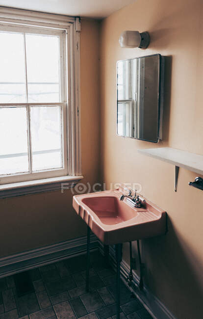 Retro vintage pink sink an mirror in an old empty dingy bathroom. — Stock Photo