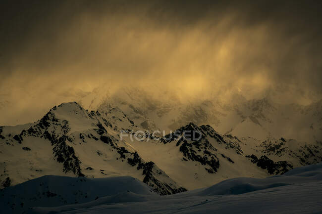 Vista panorámica de las montañas nevadas contra el cielo nublado durante el atardecer - foto de stock